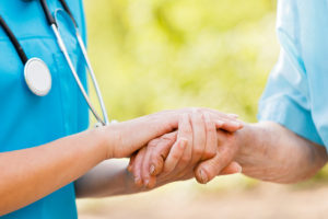 Doctor or nurse holding elderly lady's hands.